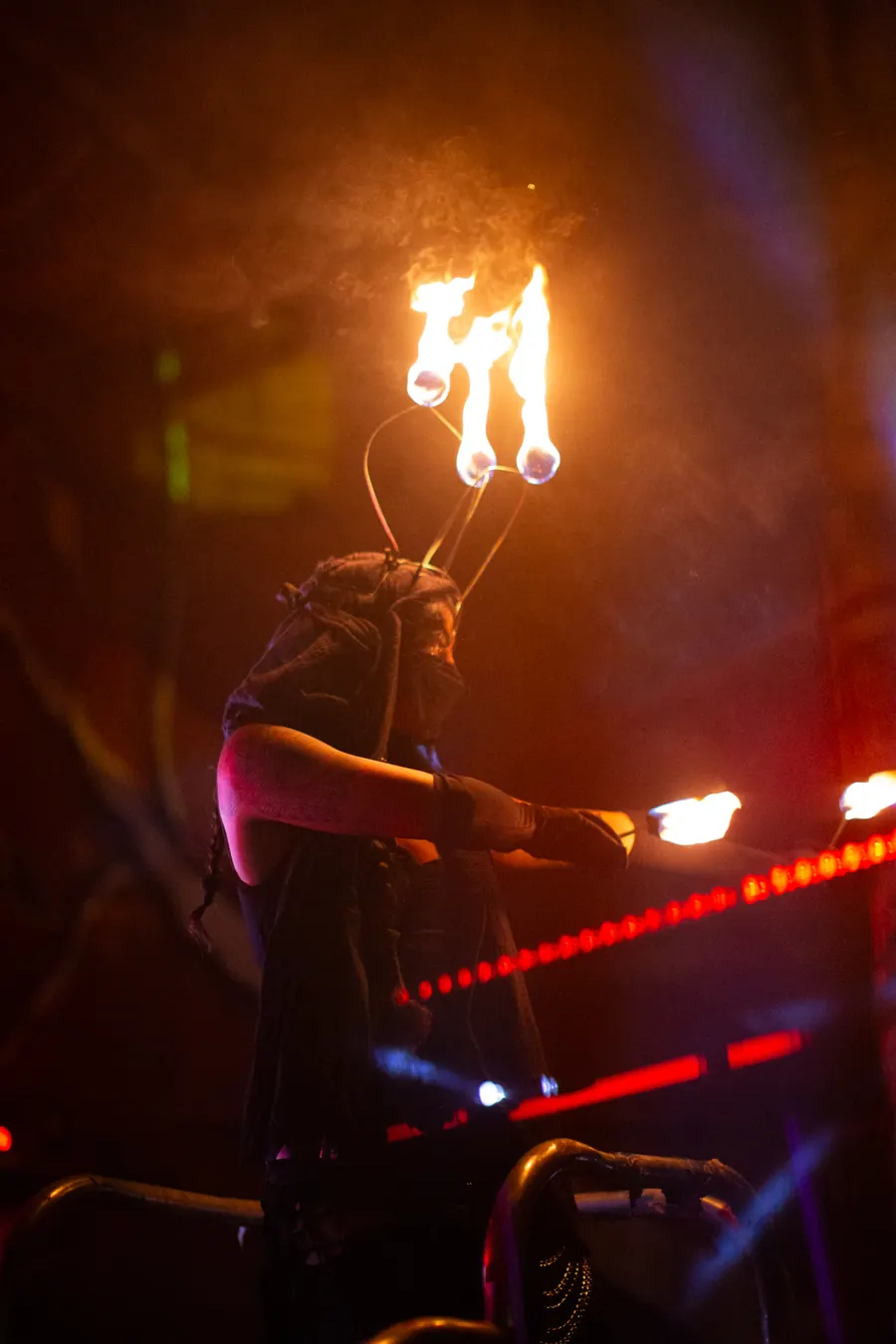 A fire performer at night with flames on top of the head